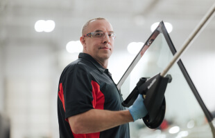 A Safelite technician wearing gloves replacing a vehicle’s rear window