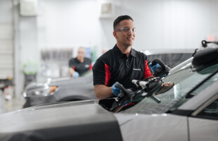 A Safelite technician wearing gloves replacing a windshield