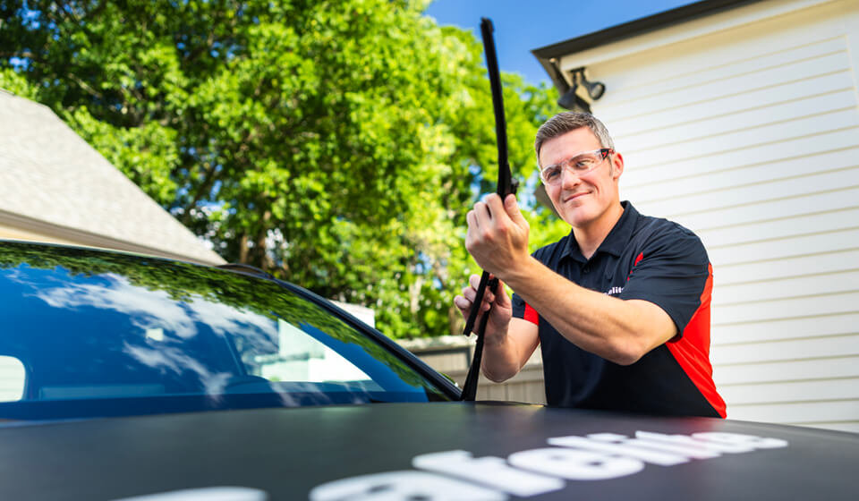 A Safelite technician installing windshield wiper blades.