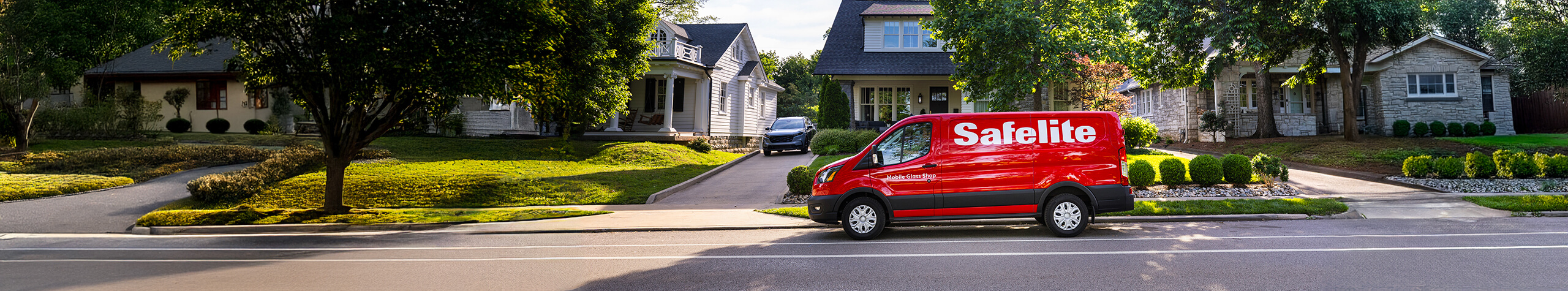 A Safelite van driving down a street.