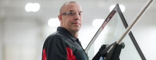 A Safelite technician wearing gloves replacing a vehicle's rear window