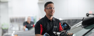 A Safelite technician wearing gloves replacing a windshield