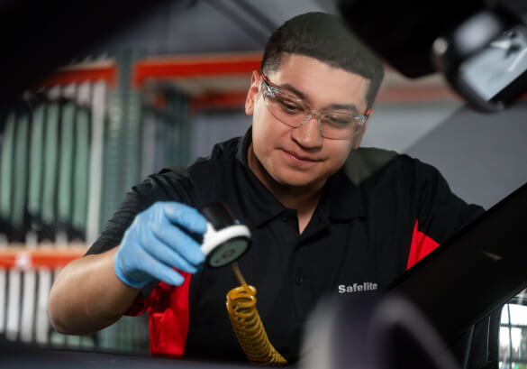 A Safelite technician wearing gloves repairing a windshield