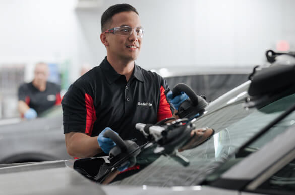 A Safelite technician wearing gloves replacing a windshield